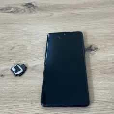 Czarny telefon i mały element głośnika na drewnianym tle.