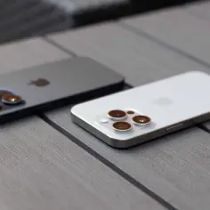 Dwa iPhone'y na drewnianym blacie. Dowiedz się, jak ustawić wibracje w iPhone, aby nie przegapić ważnych powiadomień.