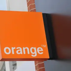 Pomarańczowy szyld z napisem "orange" i symbolem TM. To logo sieci komórkowej, które może być związane z numerem poczty głosowej Orange.