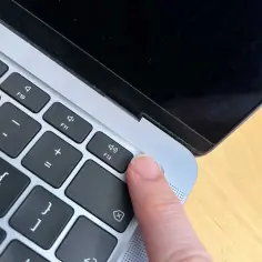 Palec naciska klawisz F12 na klawiaturze MacBook'a.
