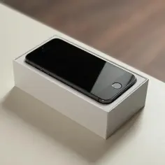 Czarny iPhone w białym pudełku na jasnym tle.