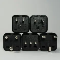 Pięć czarnych wtyczek elektrycznych, każda z oznaczeniem 250V, pokazuje różne normy napięcia w sieci.