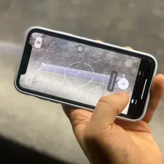 Dłoń trzyma telefon, na ekranie którego widać wirtualną miarkę cm.
