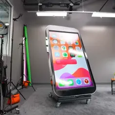 Gigantyczny telefon na kółkach, największy telefon na świecie, stoi w studiu.