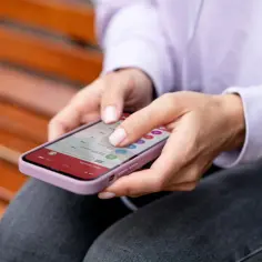 Kobieta szuka w ustawieniach telefonu, jak wyłączyć wibracje iPhone, aby skupić się na mailach.