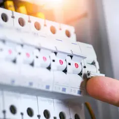 Palec naciska dźwignię wyłącznika w skrzynce elektrycznej, pokazując, jak wymienić bezpiecznik.
