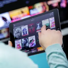 Osoba przegląda seriale na tablecie, szukając sposobu, jak pobrać serial z Netflixa na komputer.
