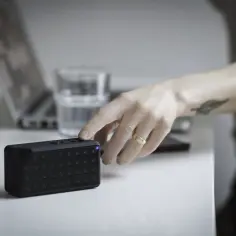 Dłoń naciska przycisk na głośniku Bluetooth, próbując rozwiązać problem, jak zresetować Bluetooth w telefonie.