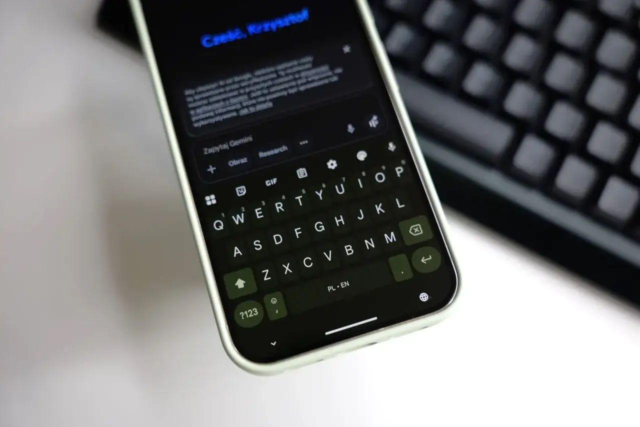 Klawiatura Gboard na telefonie wyświetla zapytanie do Gemini. Widoczny jest pasek wyszukiwania i klawisze QWERTY.