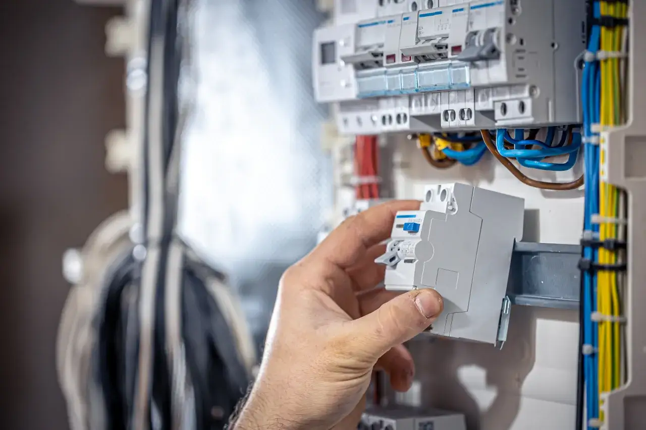 Ręka wymienia bezpiecznik w skrzynce elektrycznej. Dowiedz się, jak wymienić bezpiecznik w skrzynce, aby zapewnić bezpieczeństwo.