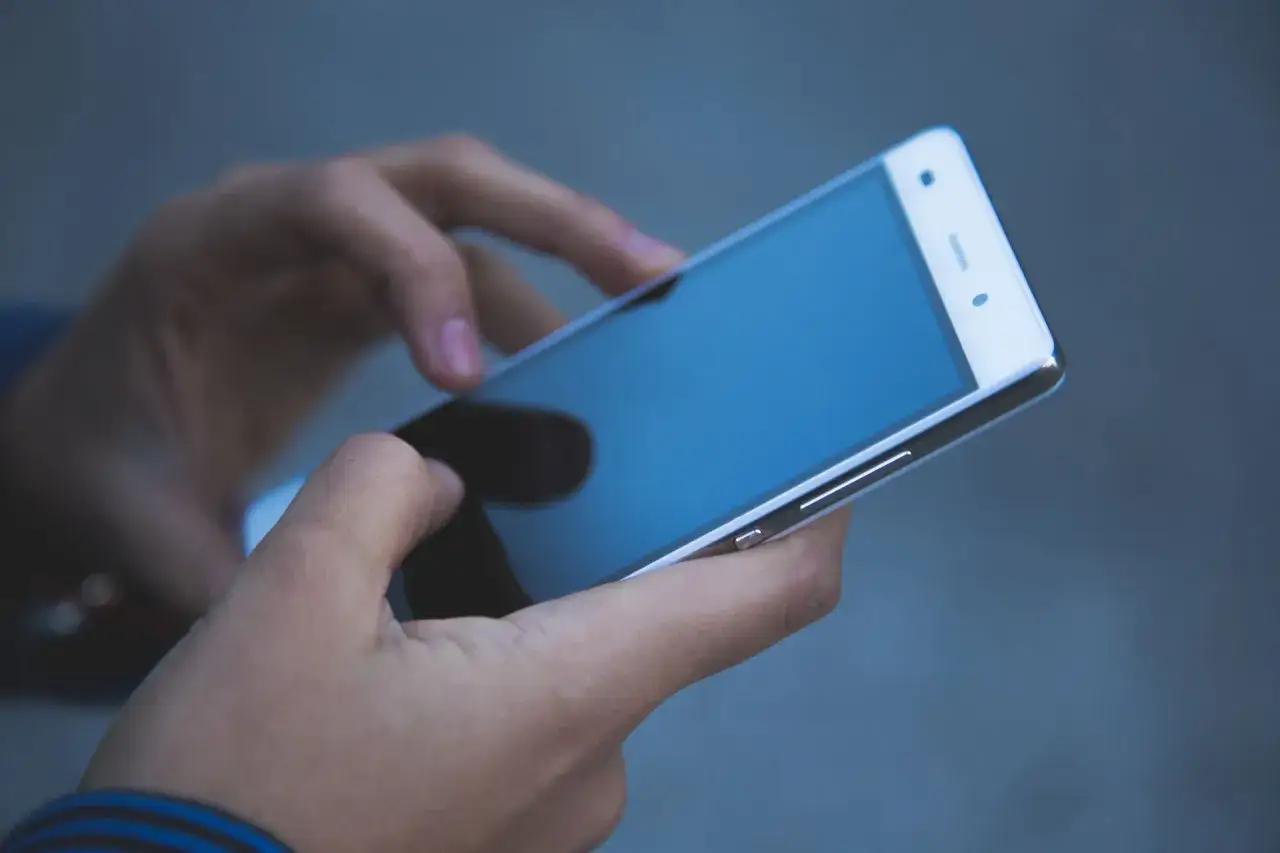 Dłoń trzyma smartfon, na ekranie wyświetla się numer poczty głosowej Orange.